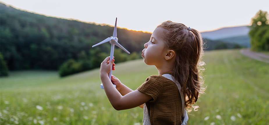 Little girl in a Michigan meadow playing with a wind turbine model